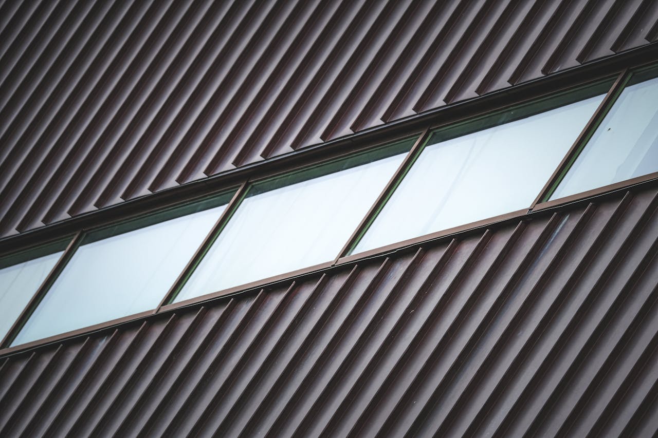 High-angle view of a modern building facade with metal panels and diagonal windows. Ideal for architectural themes.