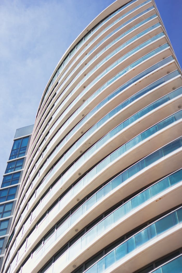 A modern skyscraper with a curved glass facade set against a clear blue sky, showcasing contemporary architecture.